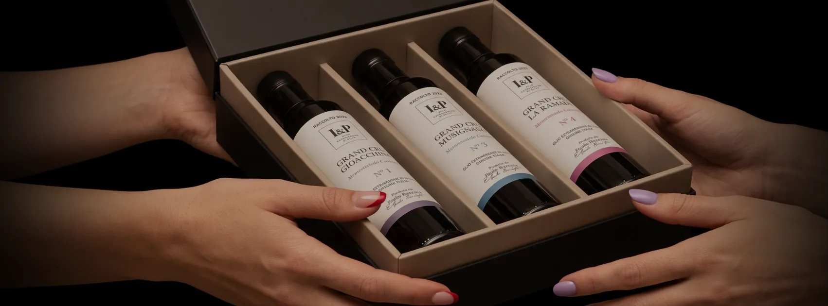 Mani che si passano un cofanetto I&P con tre bottiglie di olio extravergine